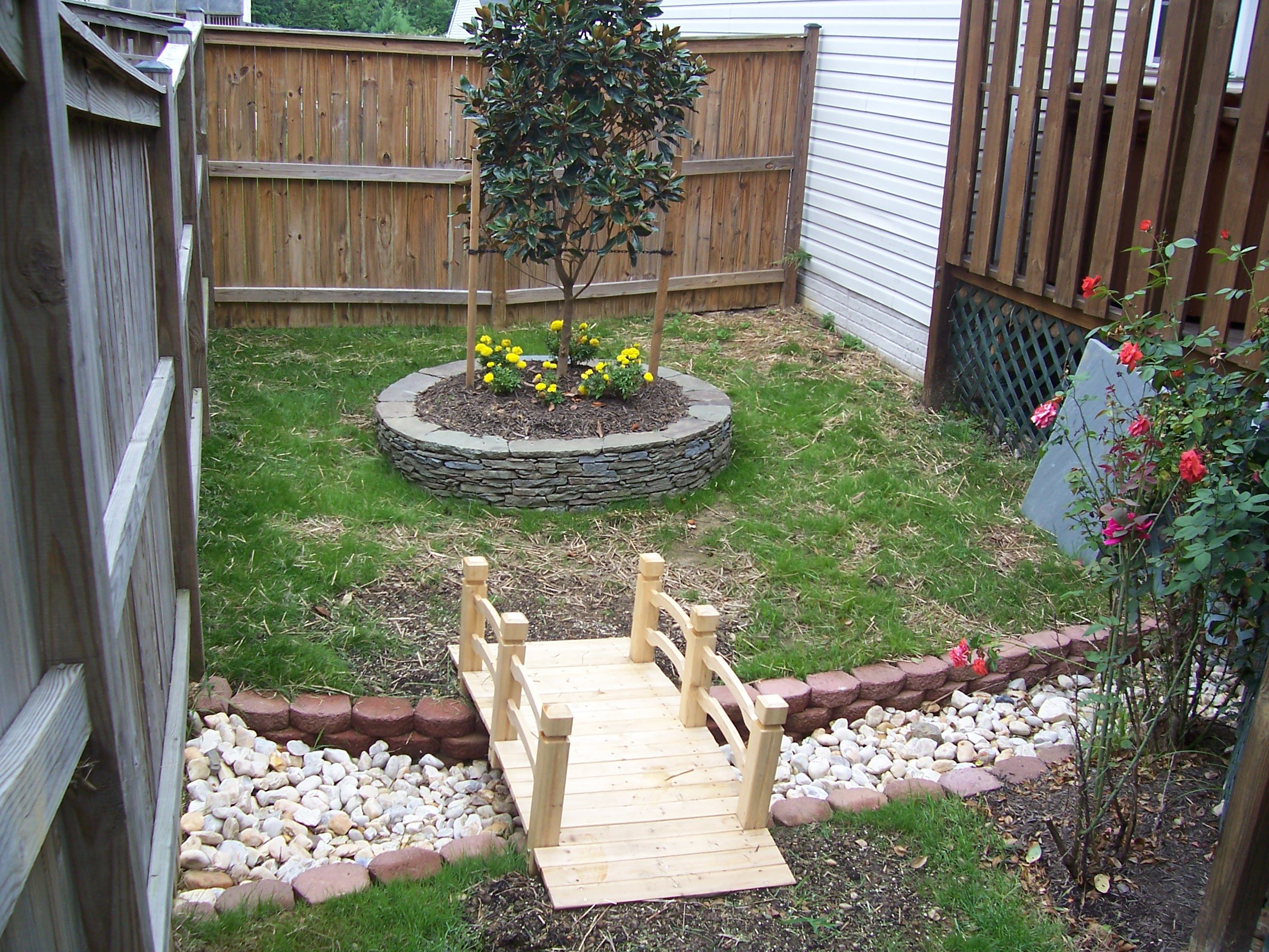 A small garden with a wooden bridge and flower bed.