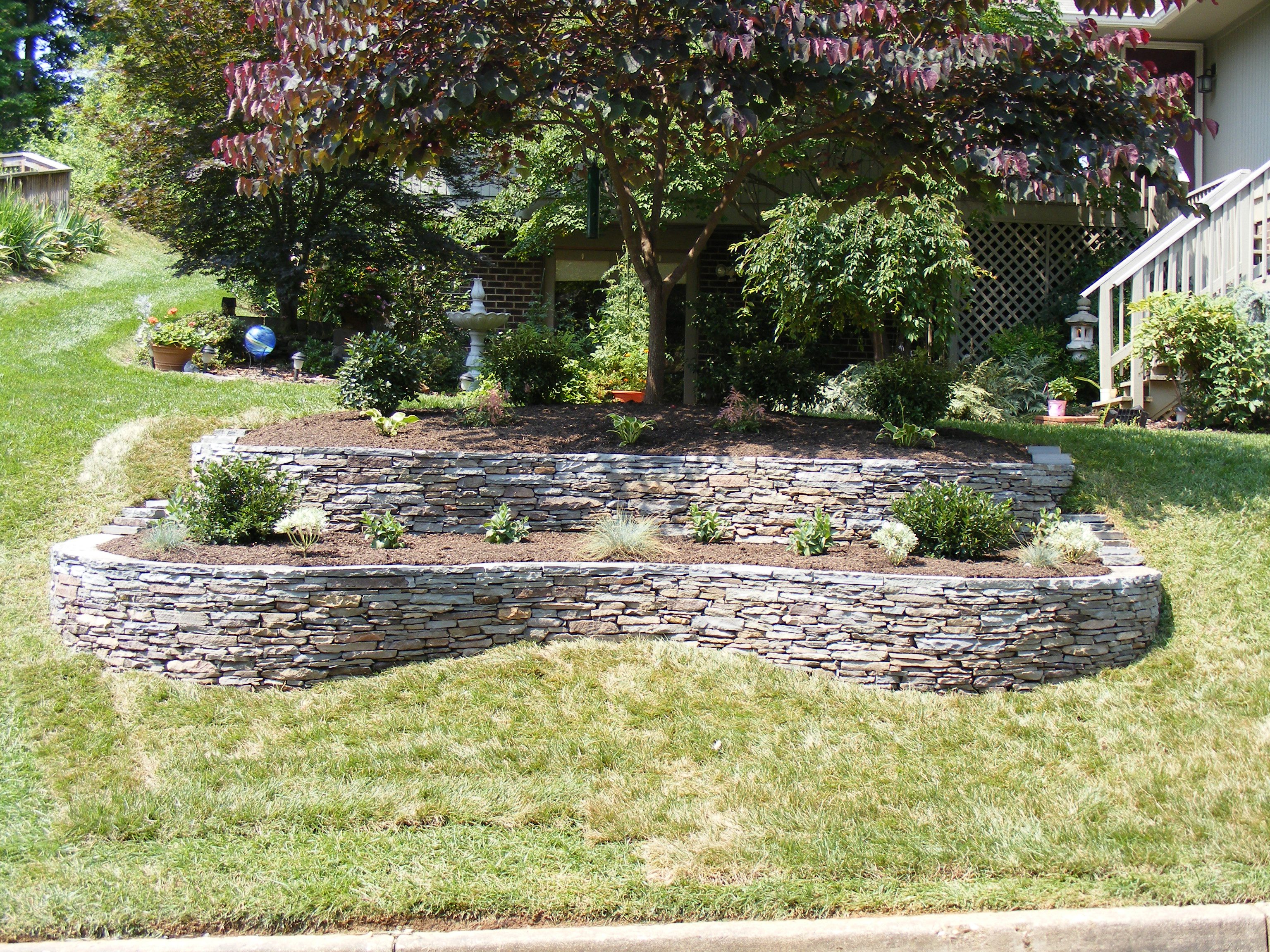 A stone wall in the middle of a yard.