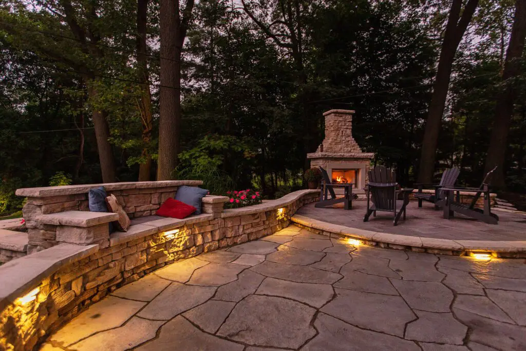 A patio with a bench and fire place in the middle of it.