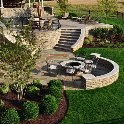 A patio with fire pit and stairs leading to the backyard.